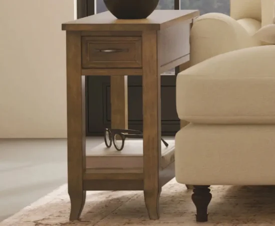Wooden side table with drawer beside a sofa.