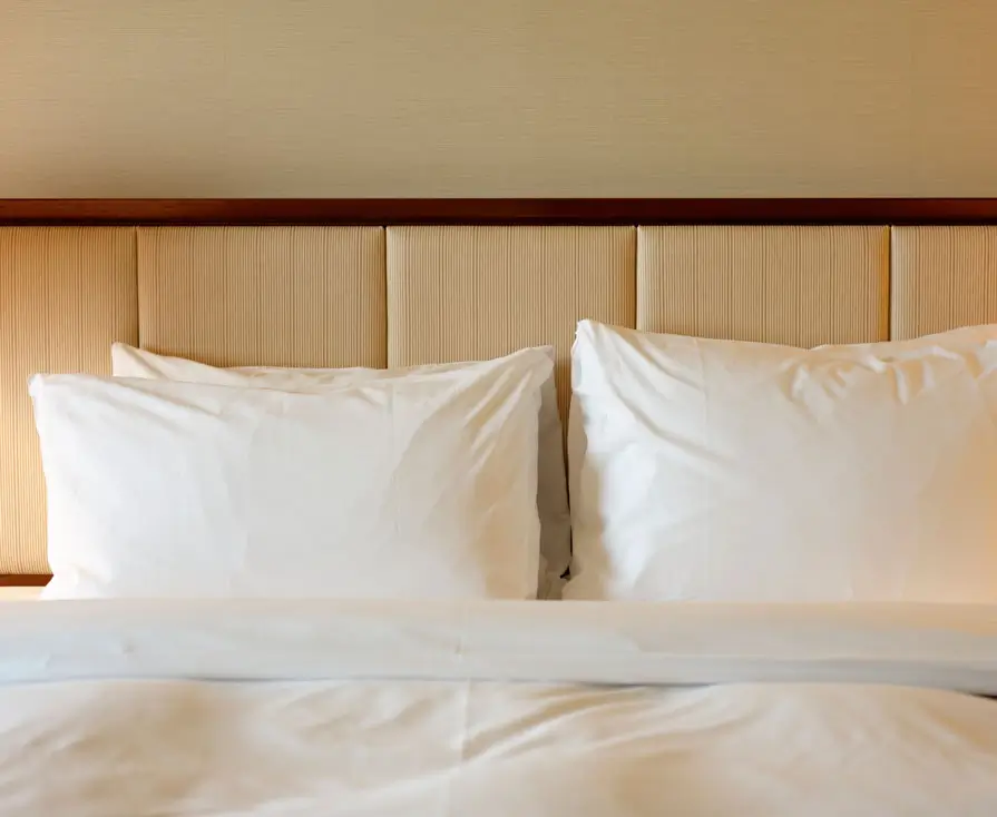 Hotel bed with white pillows and headboard