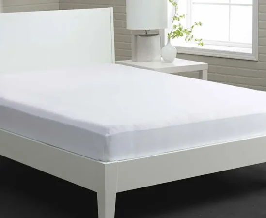 White bed with fitted sheet and nightstand.