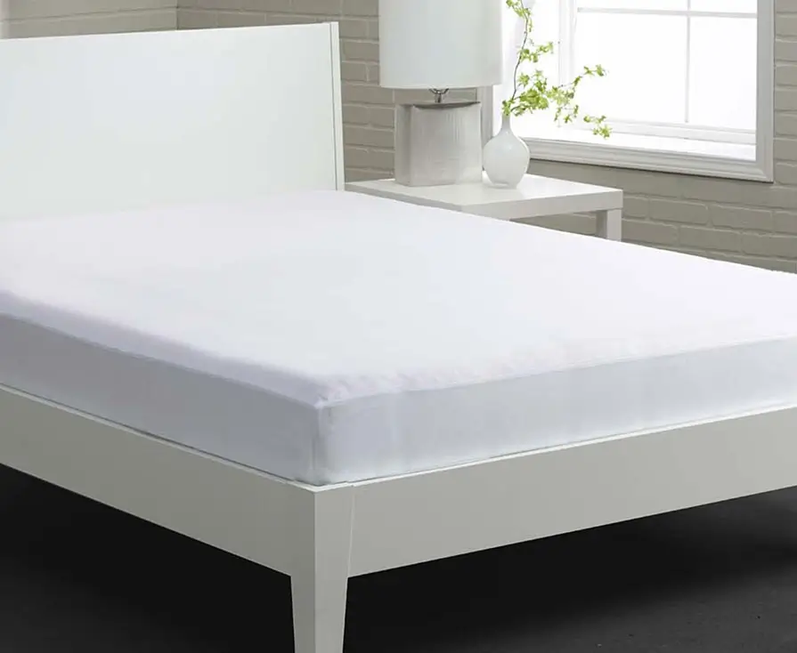 White bed with fitted sheet and nightstand.