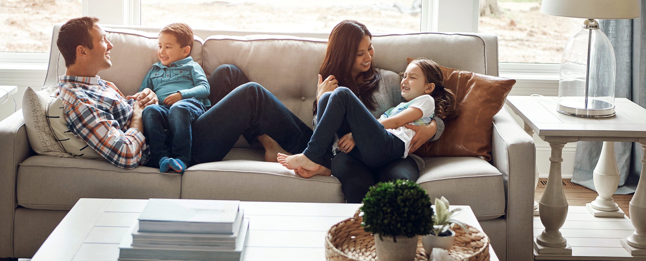 Family laughing together on living room sofa